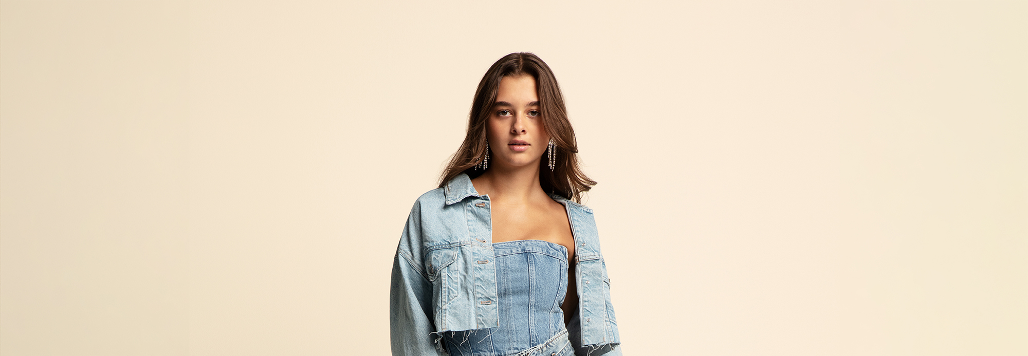 A woman wearing a denim jumpsuit and jacket